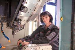 Eine Mitarbeiterin steht an einer Maschine und lächelt | © Wendelstein Werkstätten