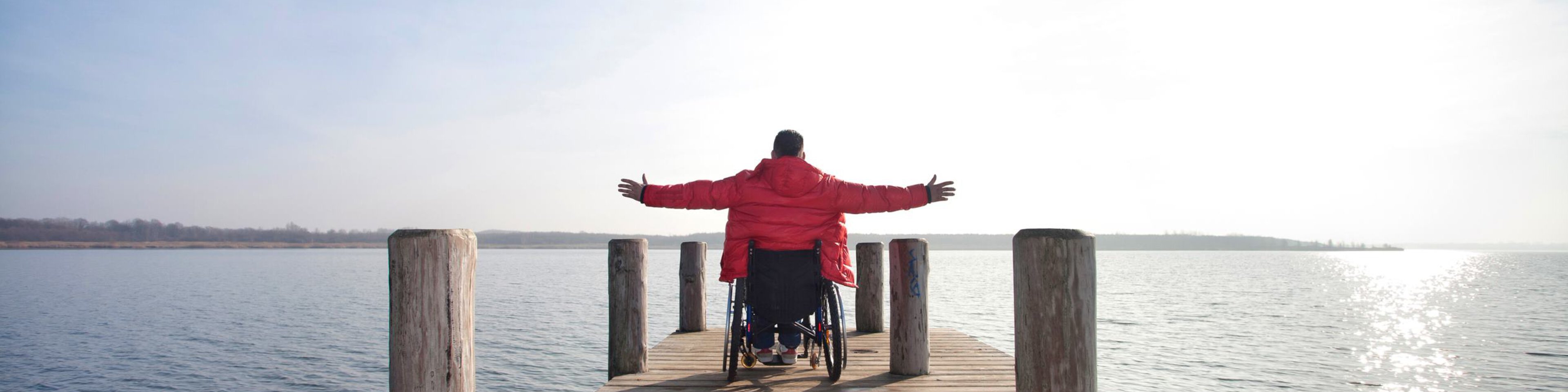 Mann im Rollstuhl auf einem Steg und breitet die Hände aus | © Wendelstein Werkstätten